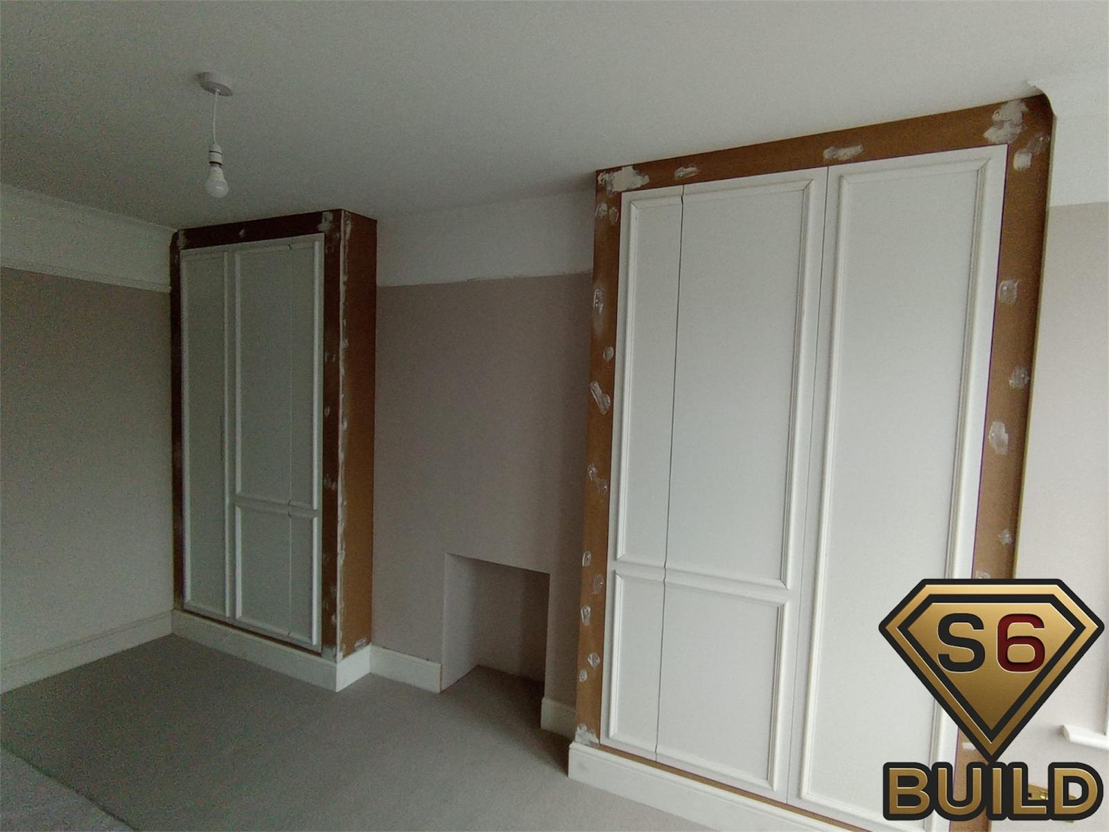 Shaker-style alcove wardrobes fitted on both sides of a bedroom chimney breast